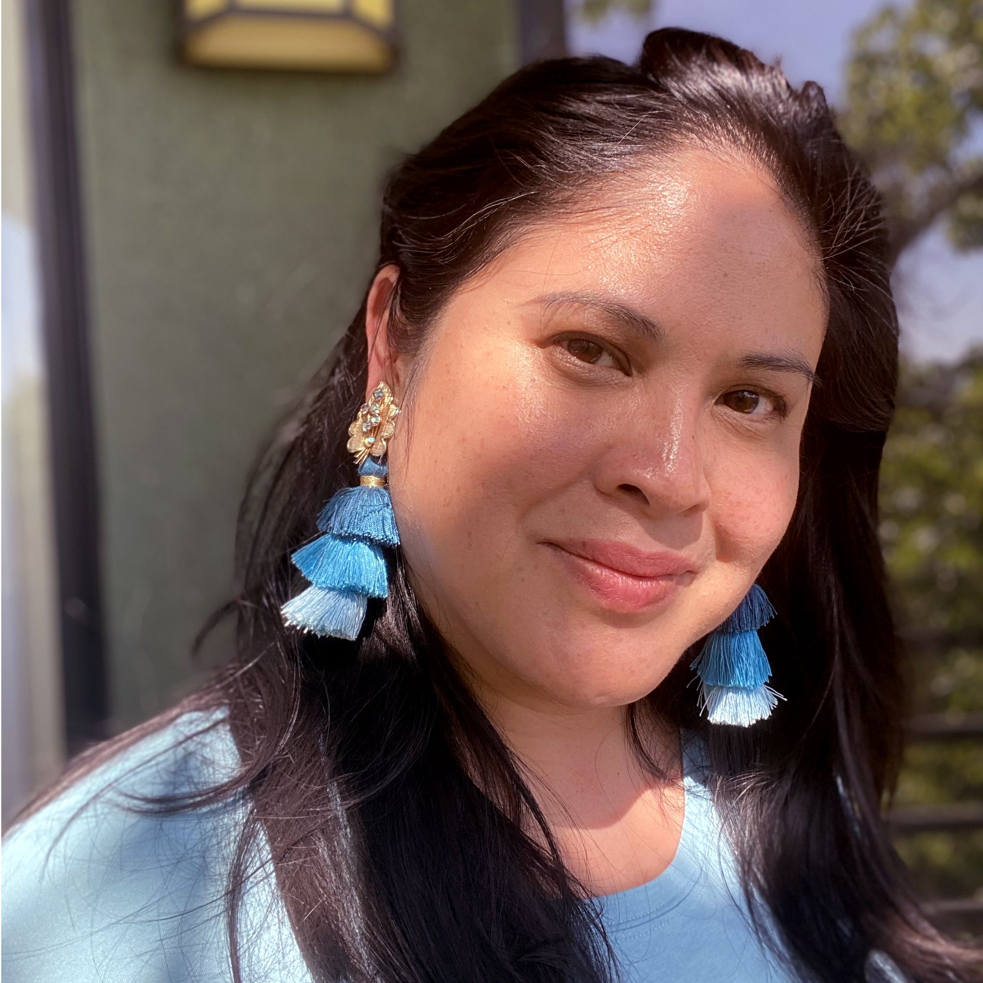 Jenny Dayco wearing iridescent leaf and blue tassel clip on earrings
